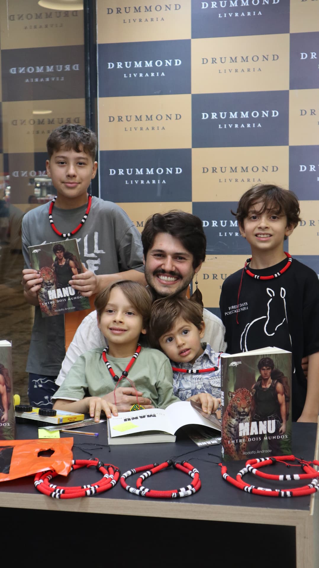 Rodolfo Andrade com jovens leitores segurando o livro Manu na sessão de autógrafos